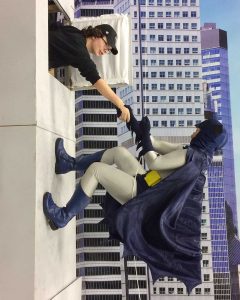 cosplayer pretends to be 1966 Batman climbing wall